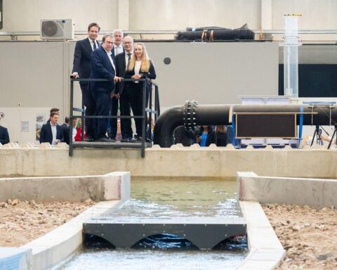 Wissenschaftler erklären Hochwasserschutz. Politiker und Experten beobachten Wasserstau am Brückenmodell.