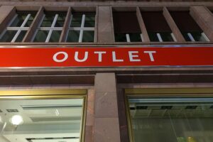 Menschen in einem belebten Outlet, diskutieren über Sonntagsöffnungszeiten des Einzelhandels.