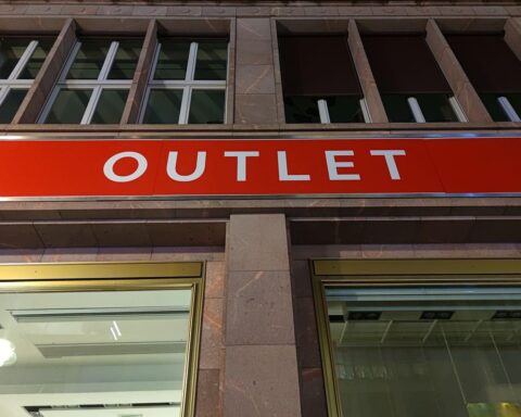 Menschen in einem belebten Outlet, diskutieren über Sonntagsöffnungszeiten des Einzelhandels.