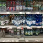 Menschen trinken aus Wasserflaschen: Rekordkäufe von stillen und Sprudelwasser während einer Hitzewelle.