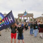 Menschen gedenken am Brandenburger Tor nach CSD-Todesfahrt: Kerzen, Blumen, Regenbogenflaggen und Schweigeminute.