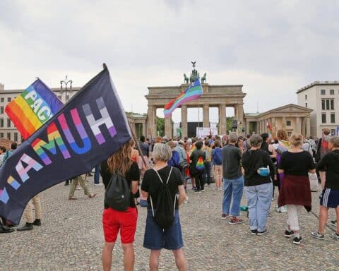 Menschen gedenken am Brandenburger Tor nach CSD-Todesfahrt: Kerzen, Blumen, Regenbogenflaggen und Schweigeminute.