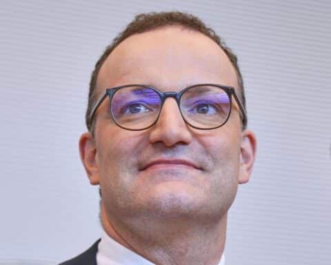 Jens Spahn lächelt, reflektiert über positives Coming-Out, umgeben von Freunden und Familie.