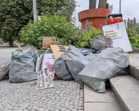 Müllsäcke mit Protestmaterial, menschenleerer Platz, Polizeiautos, Zeichen vergangener Demonstrationen.