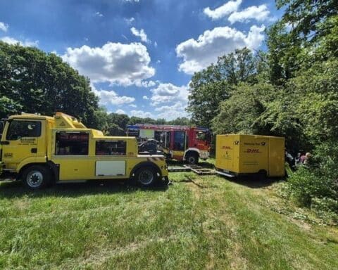 Lieferwagen hängt im Wald, Feuerwehr sichert Fahrzeug und bereitet Abschleppaktion vor.