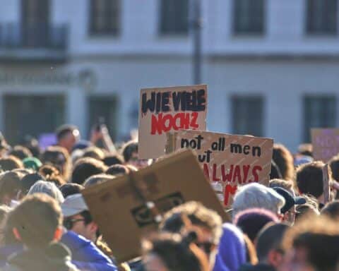Demonstration gegen digitale Gewalt: Menschen halten Plakate, fordern Schutz und Aufklärung für Frauen.