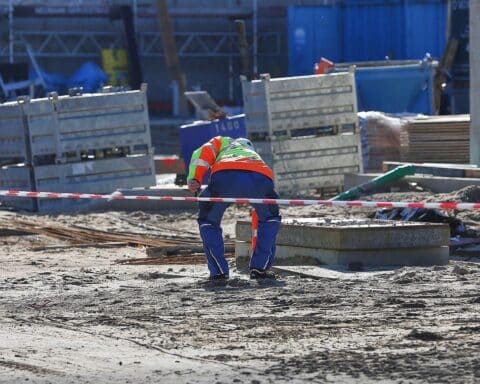 Bauarbeiter auf einer Baustelle im Sommer, gefordert: besserer Hitzeschutz und Trinkwasser für Beschäftigte.