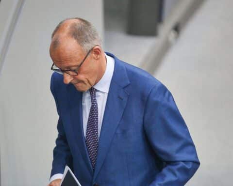 Friedrich Merz spricht, während Ines Schwerdtner ihm Realitätsferne und Schönfärberei vorwirft.