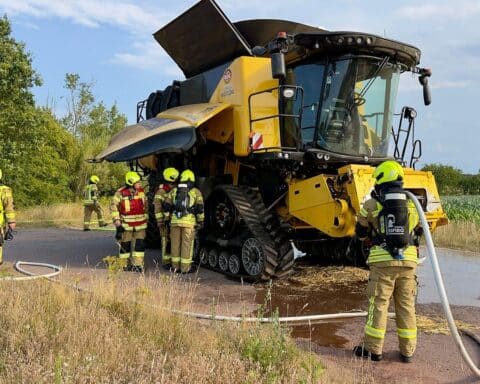 Feuerwehr bekämpft Brand eines Mähdreschers bei Erntearbeiten; starker Rauch am Fahrzeug (Archivfoto).