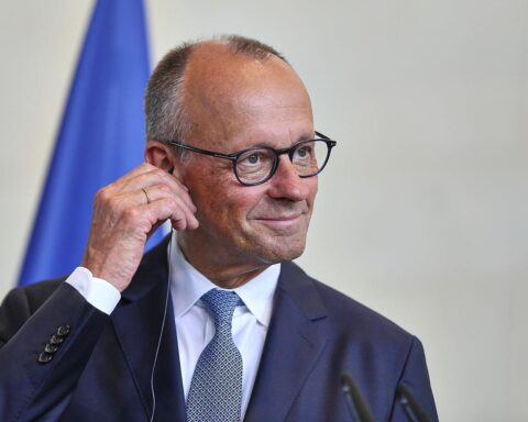 Friedrich Merz am Telefon, im Hintergrund Bezug auf Deutschland–Großbritannien und Ukraine-Unterstützung.