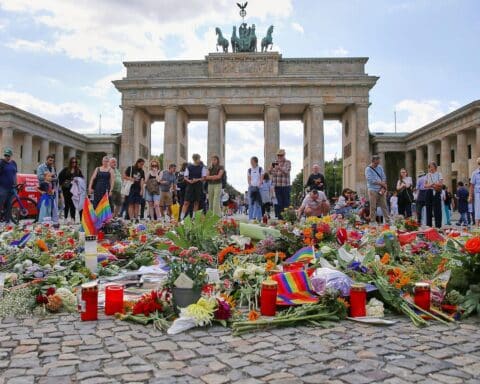 Trauernde Menschen nach CSD-Anschlag, symbolisiert Debatte über Deradikalisierung und Präventionsförderung.