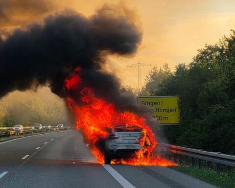 Flammen aus einem Auto, Feuerwehr im Einsatz, gesperrte Straße, Sicherheitsmaßnahmen.