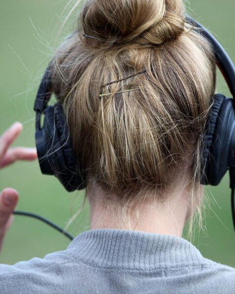 Eine Frau mit Kopfhörern, die Musikgenuss symbolisiert, passend zur Album- und Chartnews.