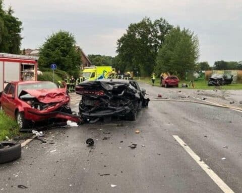 Zwei verunfallte Autos auf der Straße, Rettungsfahrzeuge, Polizei und gesperrte Straße.