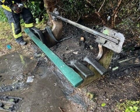 Beschädigte Sitzbank auf Spielplatz, zeugend von Brand, Feuerwehr im Einsatz, Polizei ermittelt.