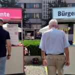 Passanten vor Infoständen zu Rente und Bürgergeld; Sozialhilfeausgaben in NRW steigen moderat 2025.