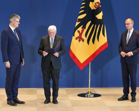 Frank-Walter Steinmeier übergibt Ernennungsurkunden; Patrick Schnieder und Friedrich Merz im Hintergrund.