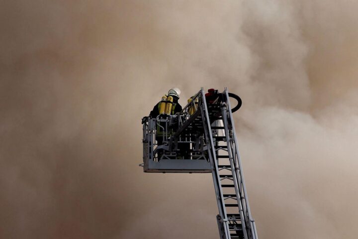 Feuerwehr auf Drehleiter (Archiv), im Hintergrund Waldbrandgefahr durch Klimawandel in Frankreich und Spanien.