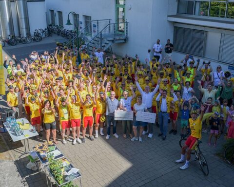Radfahrergruppe mit Begleitfahrzeugen vor Ort, bei einer Benefiz-Tour für schwerstkranke Kinder.