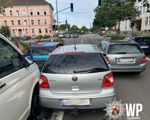 Unfallstelle mit beschädigten Fahrzeugen und Polizei im Einsatz, Fahrer verwirrt und verletzt.