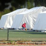 Flüchtlingskind in einer Zeltstadt vor dem Hintergrund der Forderung nach offener Flüchtlingstür.