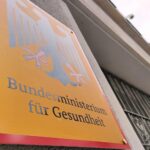 Bundesgesundheitsministerium in Berlin im Archiv: Schild/Gebäude, Hintergrund symbolisiert Wechsel und Handlungsdruck in der Pflege.