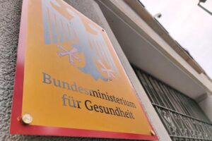 Bundesgesundheitsministerium in Berlin im Archiv: Schild/Gebäude, Hintergrund symbolisiert Wechsel und Handlungsdruck in der Pflege.
