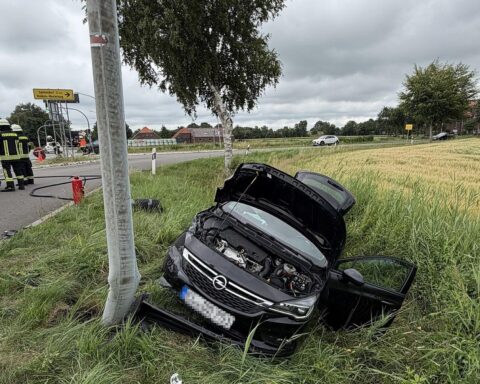 Zwei beschädigte Autos nach frontalem Unfall, einer im Straßengraben, Feuerwehr im Einsatz.