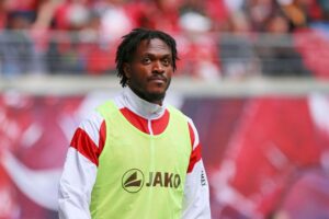 Dan-Axel Zagadou im VfB-Trikot, glücklich nach Vertragsverlängerung, Fußballplatz im Hintergrund.