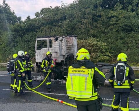 Feuerwehr löscht einen brennenden Lkw auf der Autobahn A1; Zugmaschine steht in Vollbrand.