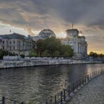 Sonnenuntergang am Berliner Reichstagsgebäude, wechselhaftes Wetter mit Wolken und trockenem Himmel.