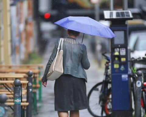 Frau mit Regenschirm bei wechselhaftem Wetter in Mecklenburg-Vorpommern (trüb, leichte Schauer möglich).