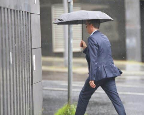 Mann mit Regenschirm im wechselhaften Wetter; Wind und Regen in Niedersachsen und Bremen.