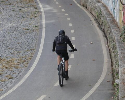 Fahrradfahrer auf Fahrradweg bei wechselnd bewölktem, teils schauerlichem Wetter (Archivfoto).