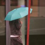 Mann mit Regenschirm im wechselhaften Wetter, schauergrau, in Nordrhein-Westfalen (Archivfoto).