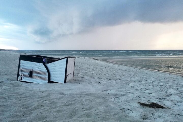 Umgekippter Strandkorb am Ostseestrand bei Gewitter, starker Wind und Sturmwarnung.
