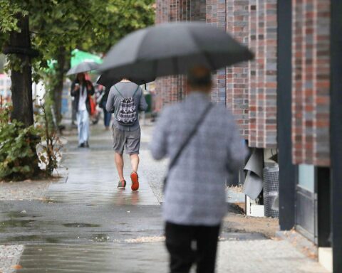 Passanten mit Regenschirm bei überwiegend bewölktem Wetter in Hamburg.