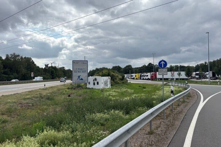 Ein verunfalltes Wohnmobil liegt auf der Seite zwischen Autobahn und Parkplatz; Einsatzkräfte am Unfallort.