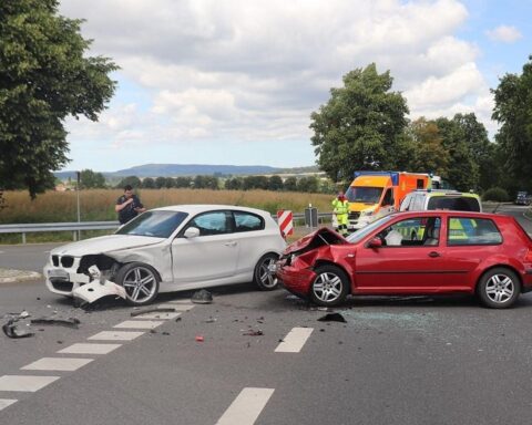 Zwei beschädigte Autos nach Unfall, Polizei und Abschleppdienste an Einsatzstelle.