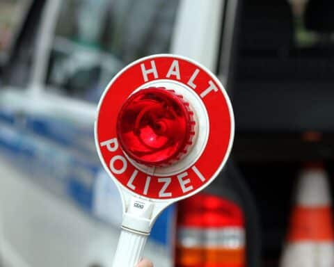 Polizeiverkehrskontrolle mit Halt-Stopp-Schild; Überprüfung von Pkw und E-Scootern wegen Fahruntüchtigkeit.