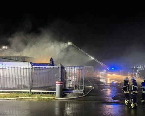 Feuerwehr, THW und Sanitäter bekämpfen nachts einen Brand in Lagerhalle eines Müllverwertungsunternehmens.