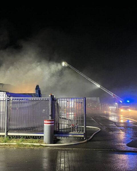 Feuerwehr, THW und Sanitäter bekämpfen nachts einen Brand in Lagerhalle eines Müllverwertungsunternehmens.