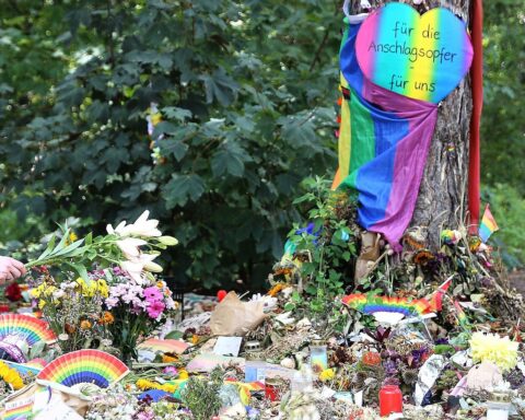Trauernde Menschen nach dem CSD-Terroranschlag in Berlin, mit besorgten Gesichtern und Gedenk-Kerzen.