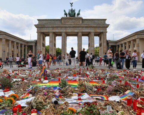 Trauernde Menschen vor Ort nach dem CSD-Anschlag in Berlin, mit Hinweis auf Forderungen nach mehr Sicherheit.