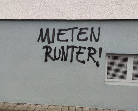 Graffiti mit Schriftzug „Mieten runter“: politische Forderung nach bezahlbarem Wohnen in Düsseldorf.
