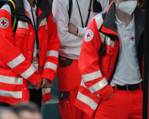 DRK-Helfer im Einsatz (Archivfoto), im Hintergrund Hinweise auf DRK-Freiwilligendienste und Zivildienst.