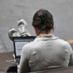 Frau mit Laptop im Archiv; Politiker warnen vor leistungsfähigen Open-Source-KI-Modellen für Cyberangriffe.