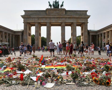 Trauerndes Umfeld nach CSD-Anschlag: Kerzen und Blumen am Tatort, Polizei im Hintergrund, Betroffenheit in Berlin.